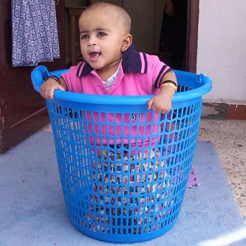 child playing in washing basket